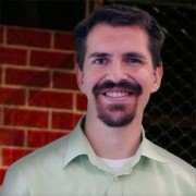 Smiling man with short dark hair, mustache and goatee